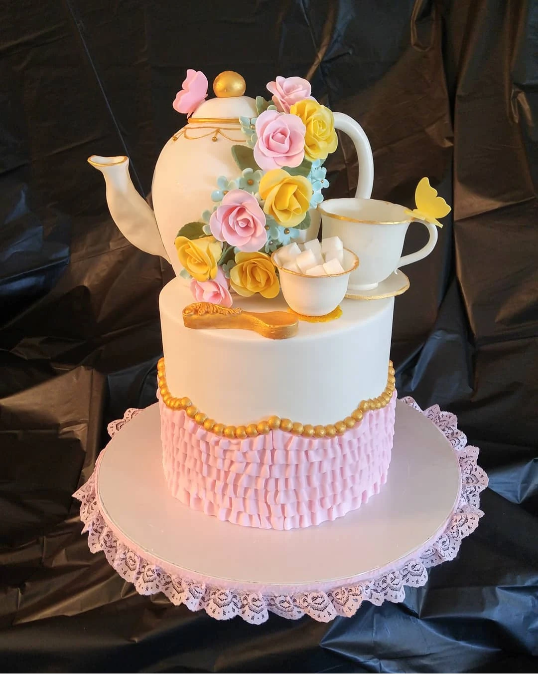 Peachy Sweets sculpted teapot cake with teacups, pastel flowers, and pink ruffled icing